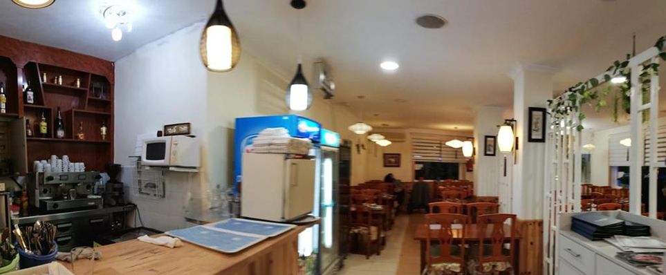 Vista desde la barra del restaurante, con la cafetera en primer plano y el comedor iluminado al fondo.