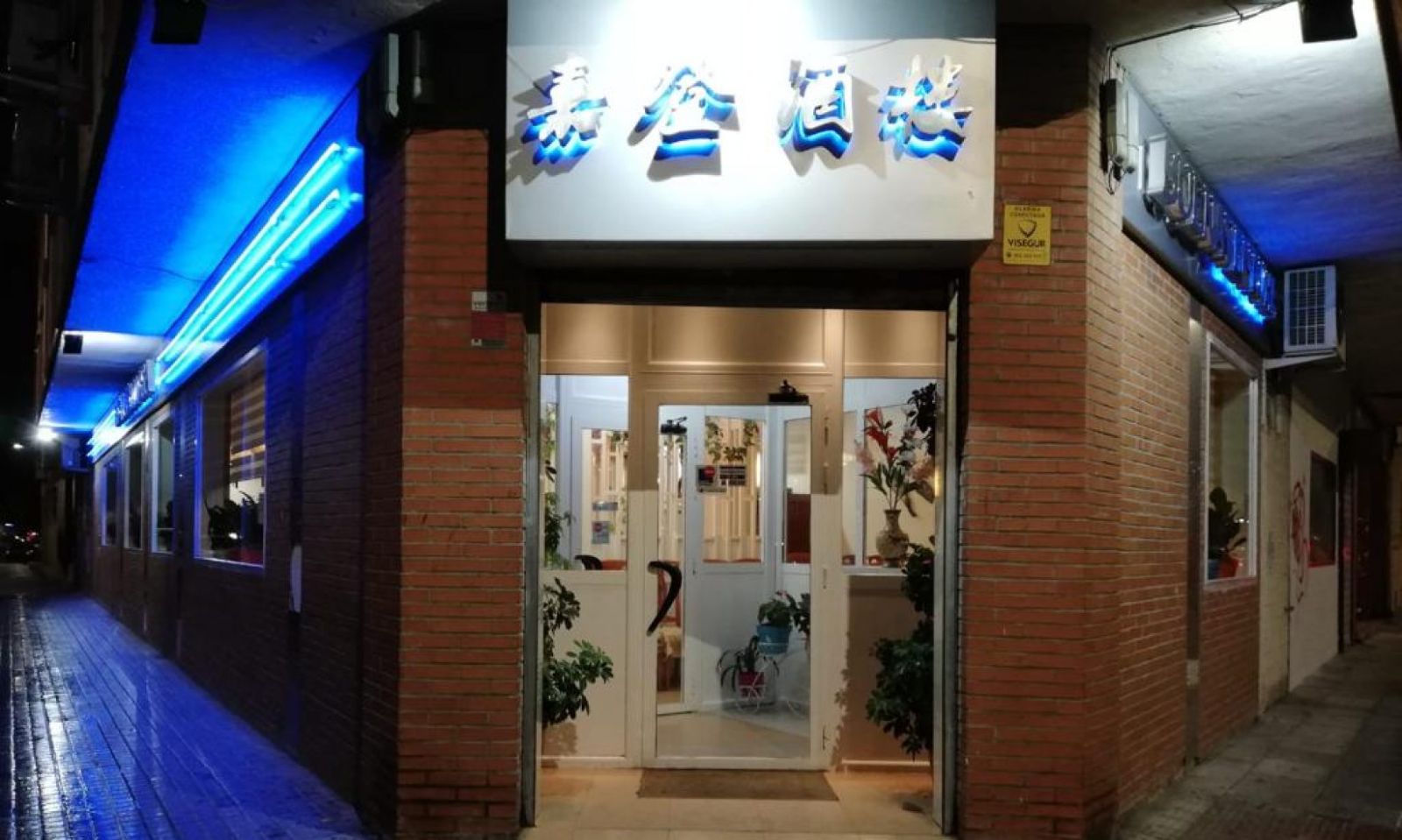 Fachada del Restaurante Buenaventura de noche, con neón azul sobre ladrillo rojo y el rótulo en caracteres chinos.
